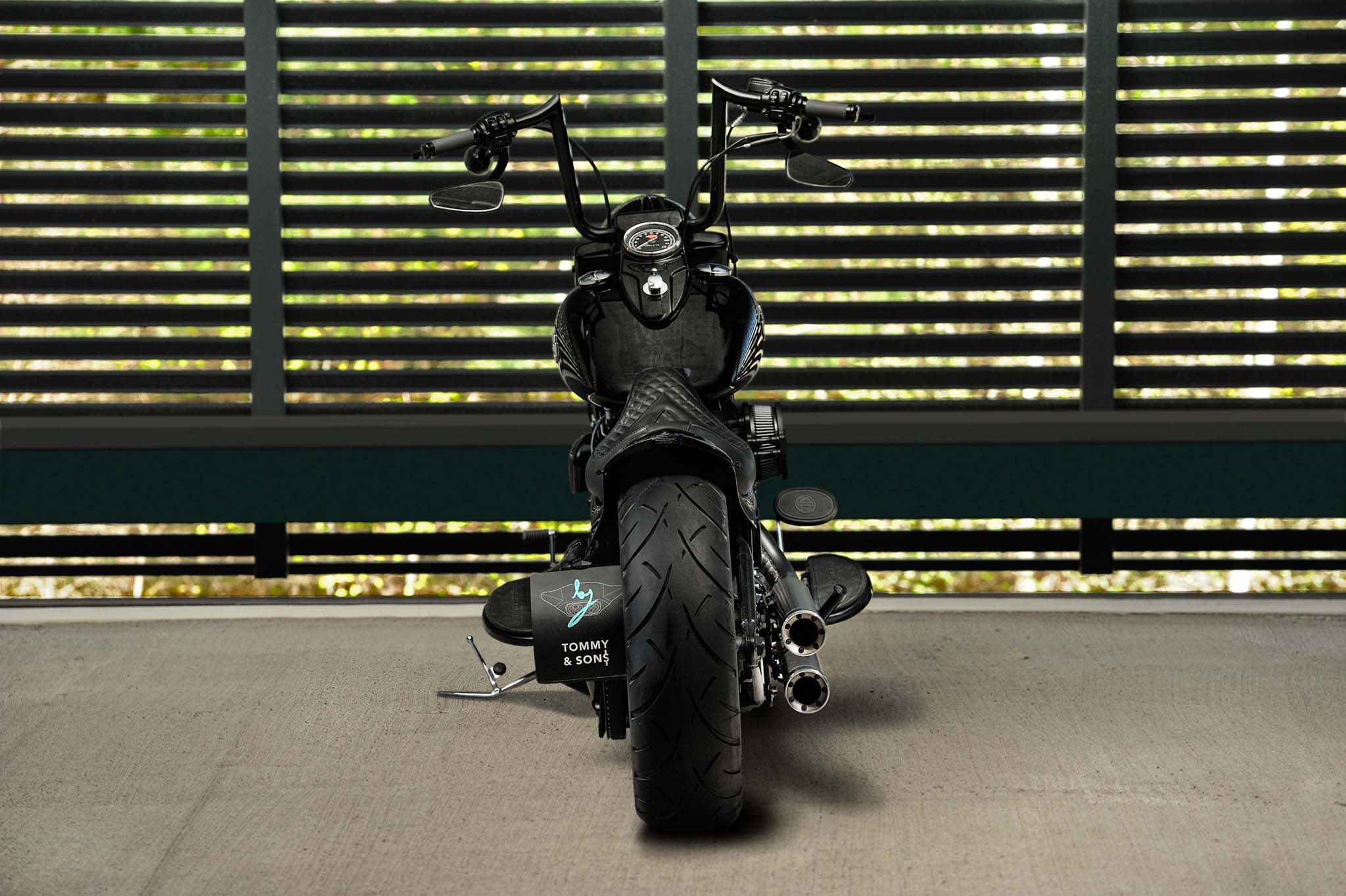 Custom Harley Davidson Softail Slim pictured from rear with a wide rear tire, bobber style short fender and ape hanger handlebar