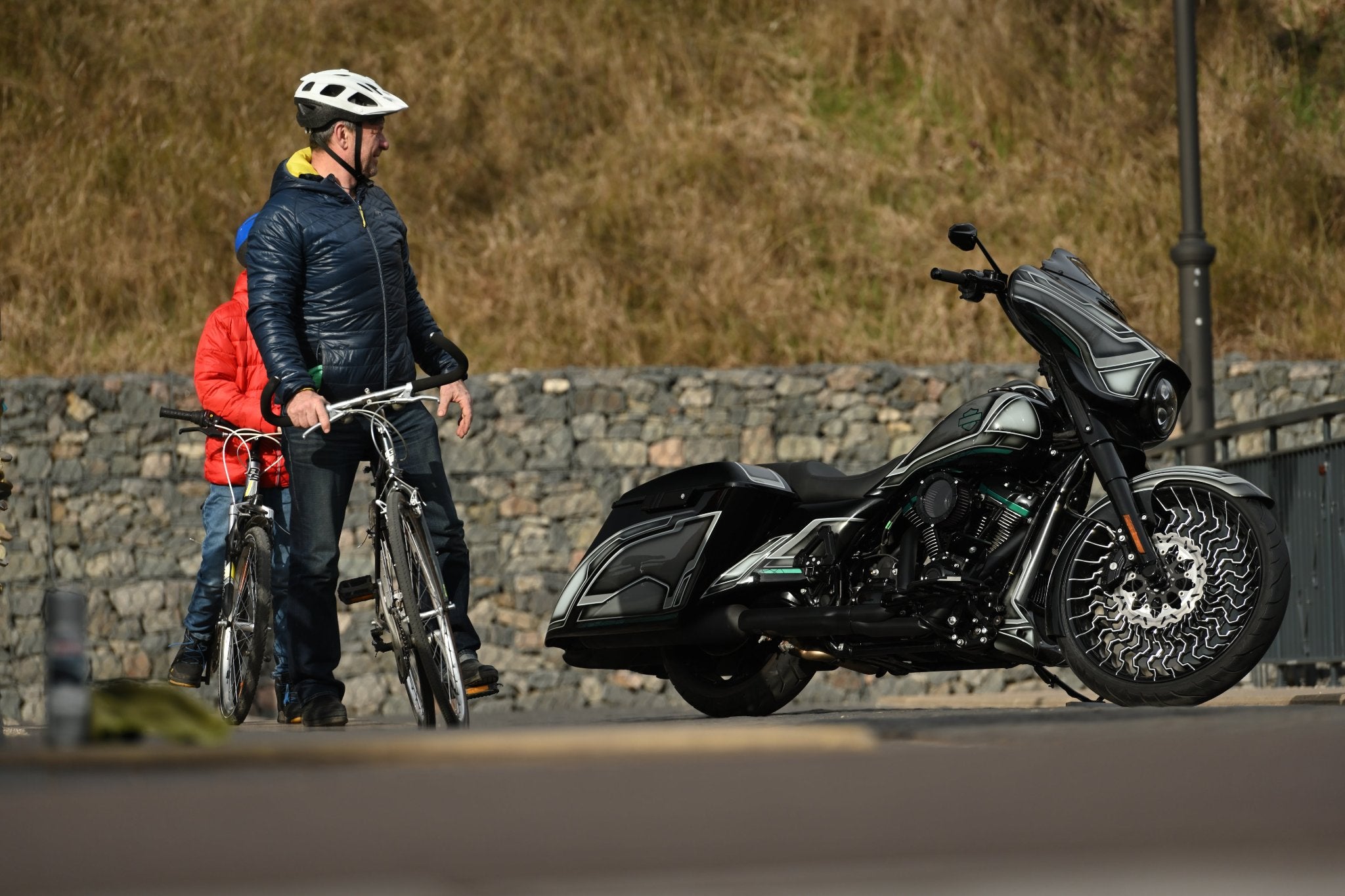 Vortex custom Harley Davidson Street Glide Special photographed from the side with bicycle riders on the left.